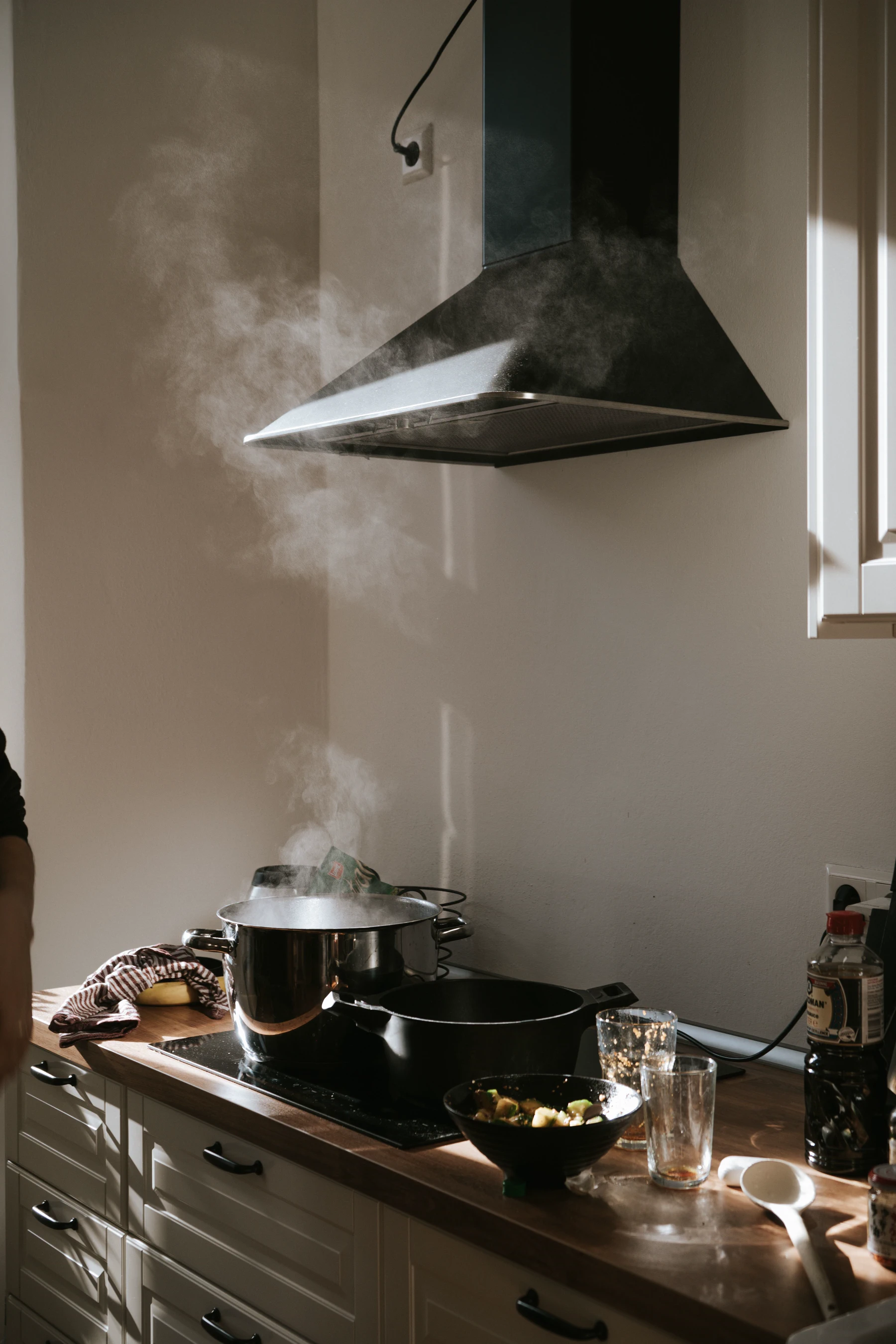 Cooking steam rises from a pot toward an extractor hood