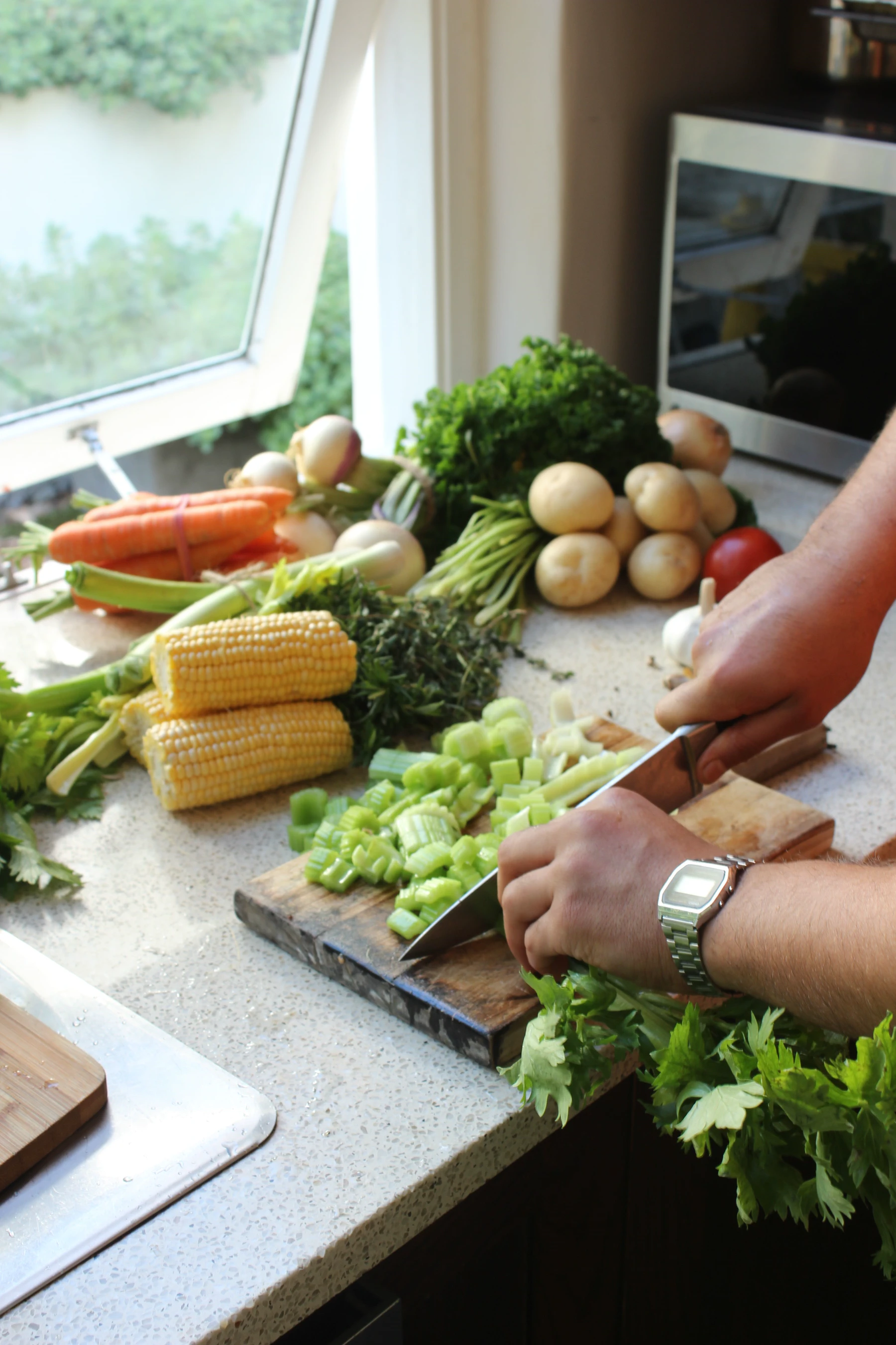 Fresh vegetables are prepared together on a kitchen work surface