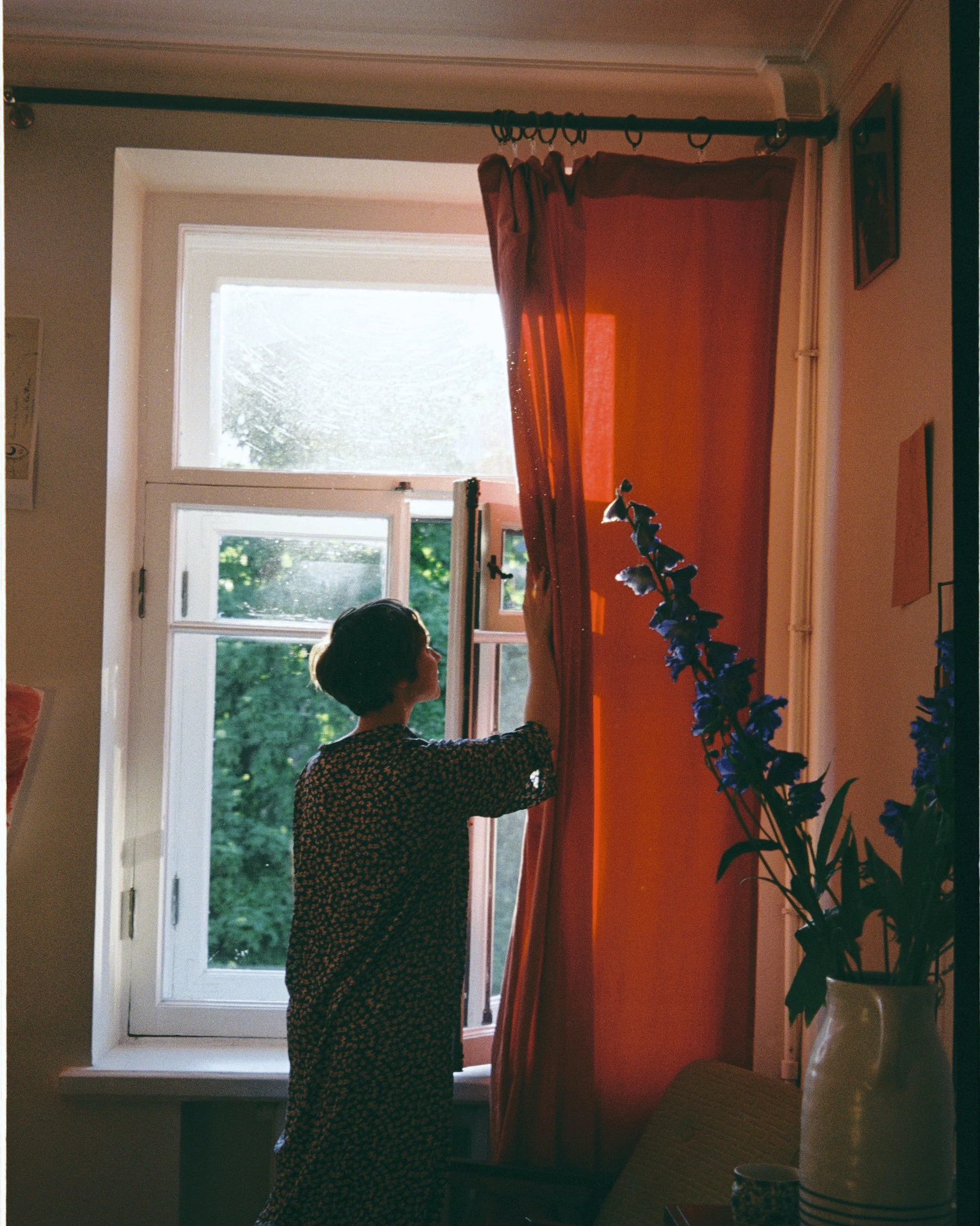 A resident opens curtains to bring morning daylight into a room