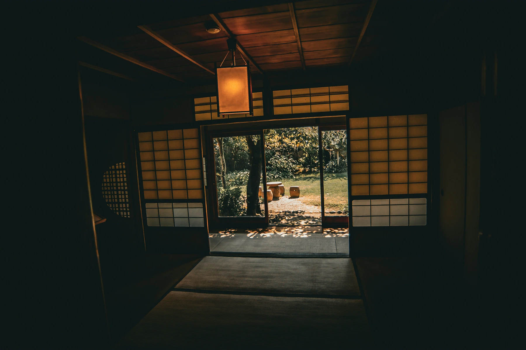 A still Japanese room opens toward a shaded garden.