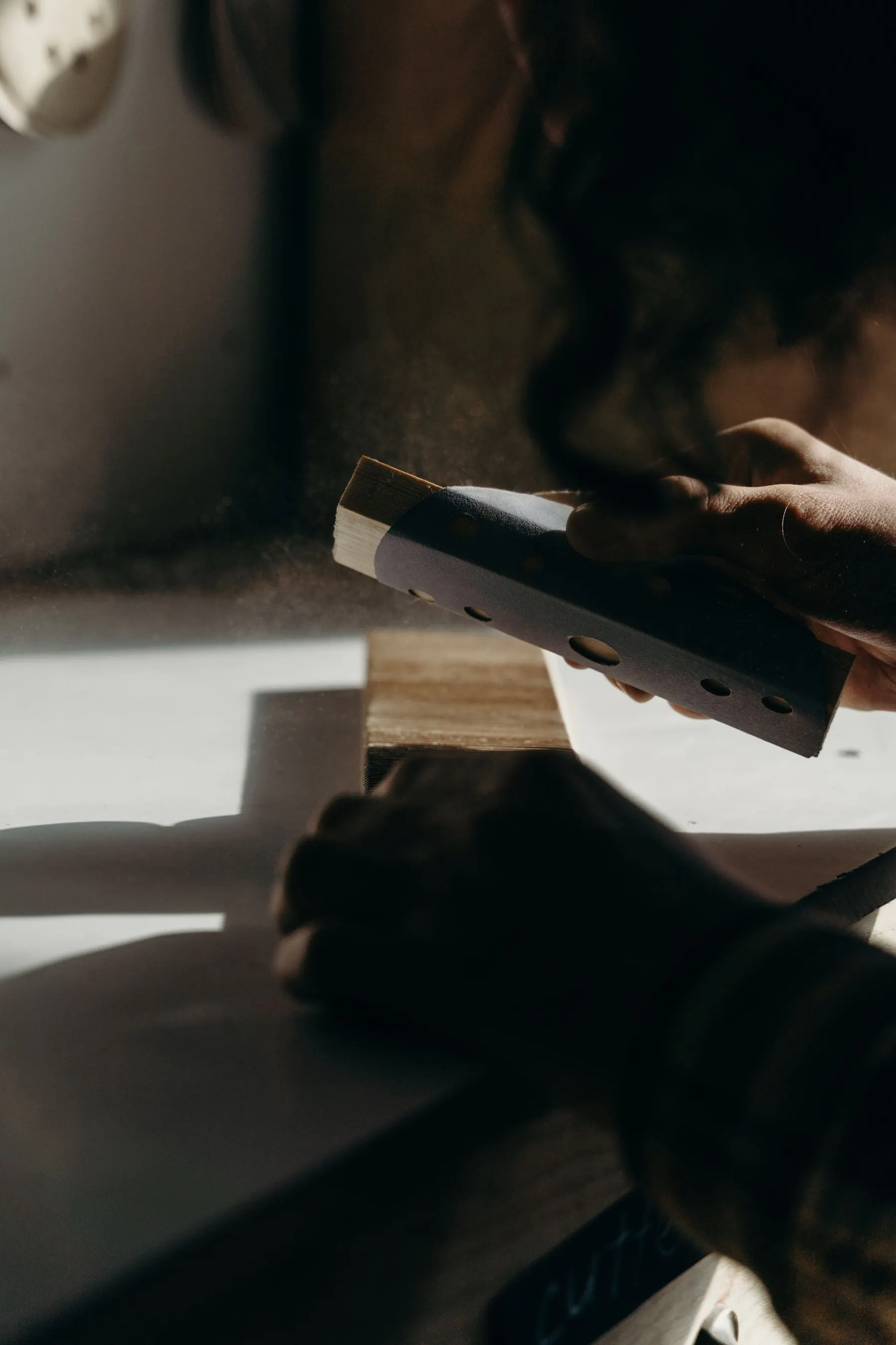 A craftsperson sands a piece of timber by hand